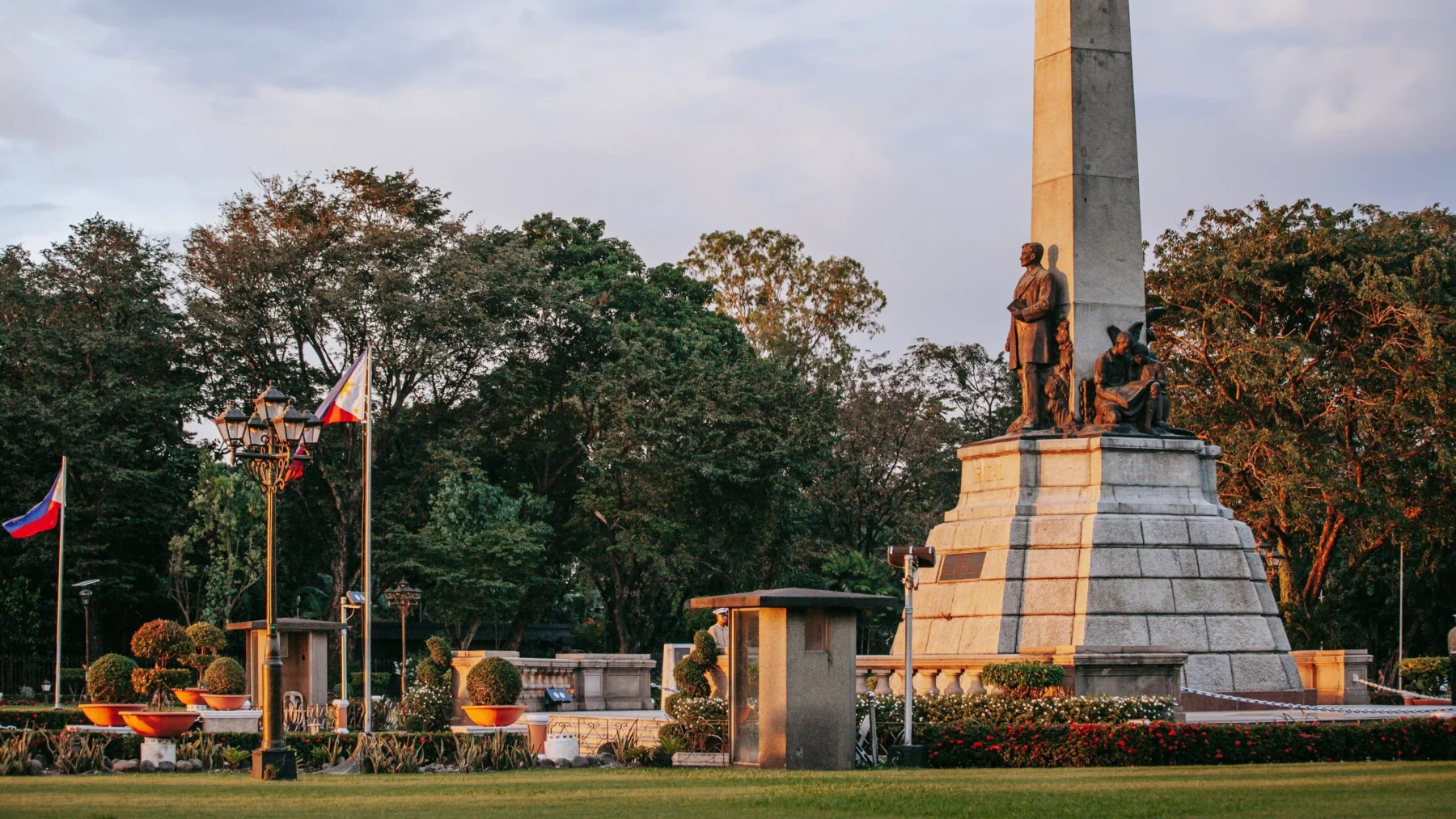 Rizal Monument at golden hour in Rizal Park Manila with Philippine flags — iconic things to do in Manila