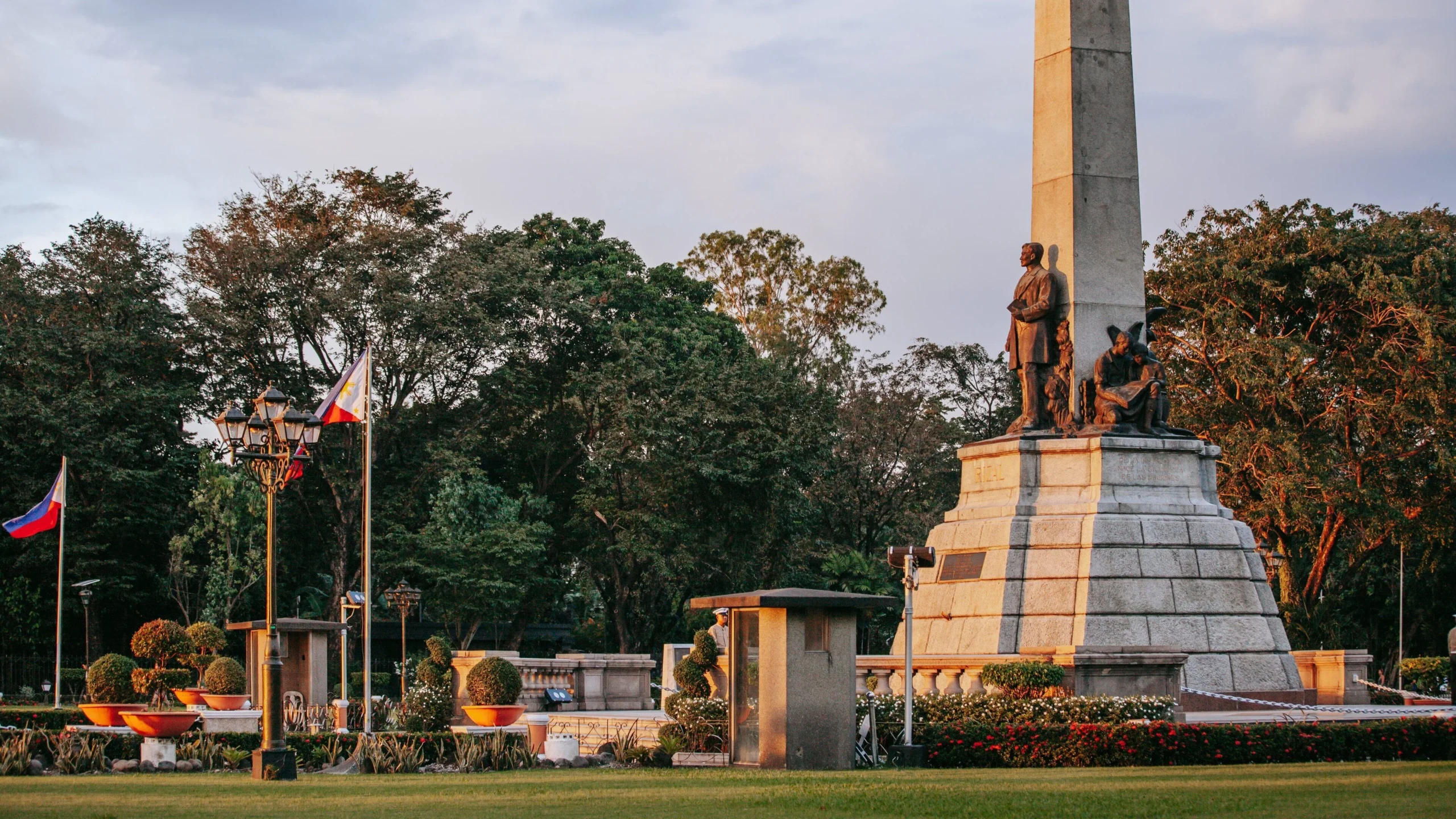 Rizal Monument at golden hour in Rizal Park Manila with Philippine flags — iconic things to do in Manila
