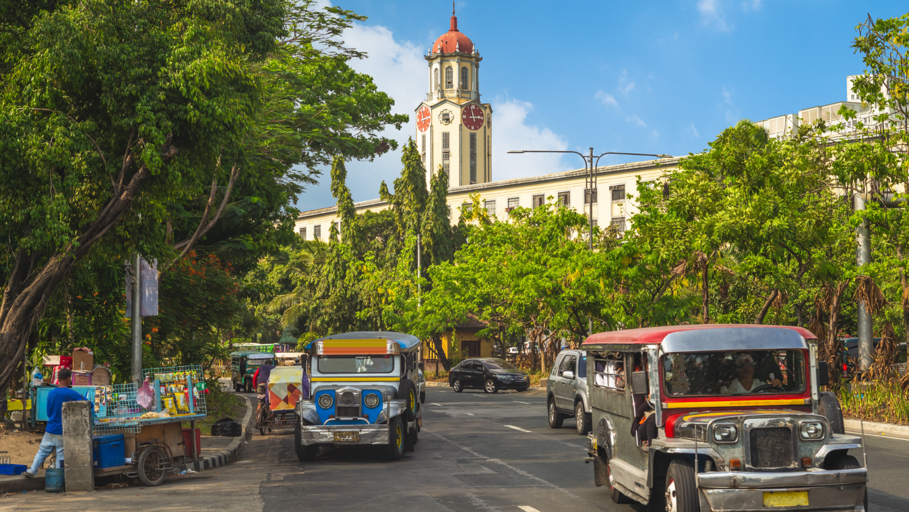 Colorful jeepneys passing historic clock tower in Manila — classic Manila attractions and daily lif