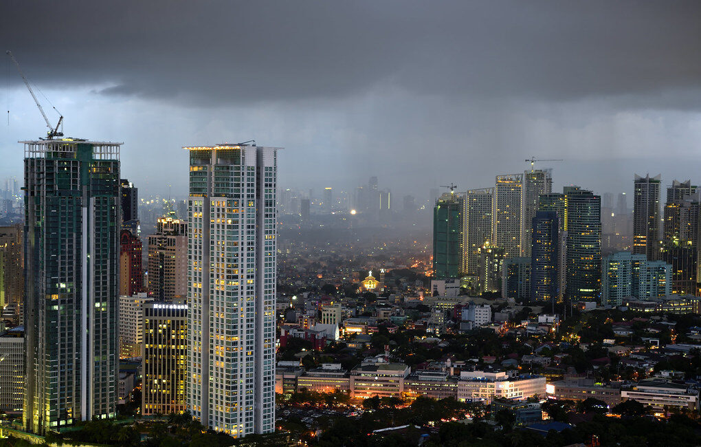Manila skyline during rainy season Philippines with dark storm clouds and city lights at dusk
