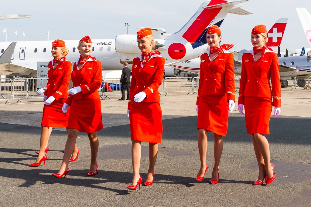 Hot air hostess Aeroflot cabin crew in red uniform walking on runway with strict grooming and coordinated presentation