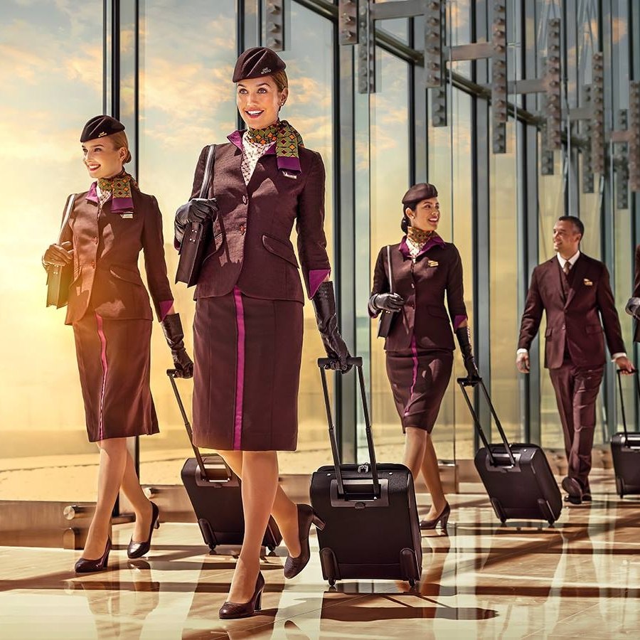 Etihad Airways hot air hostess uniform showing professional cabin crew walking with luggage in coordinated service presentation