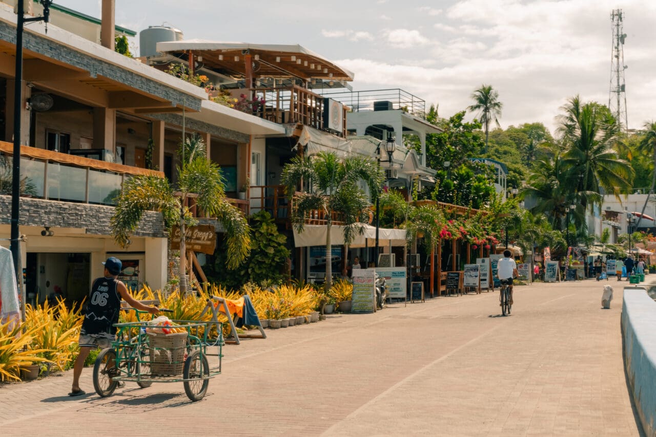 Everyday street scene in Puerto Galera, Philippines with locals going about their daily routines, capturing the relaxed rhythm of life beyond the tourist highlights