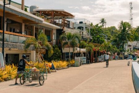 Everyday street scene in Puerto Galera, Philippines with locals going about their daily routines, capturing the relaxed rhythm of life beyond the tourist highlights