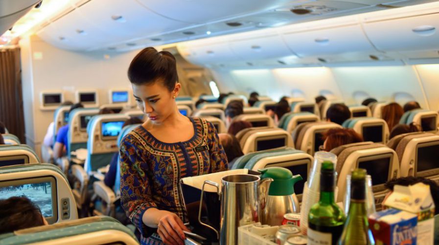 Flight attendant serving passengers in economy cabin showing controlled service behavior and emotional labor