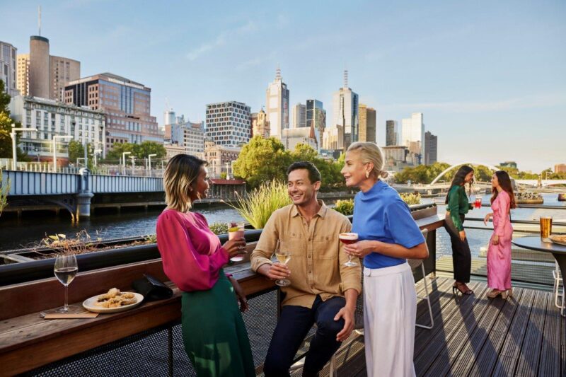 Group of people having a casual conversation at a rooftop bar in Melbourne, Australia, illustrating Australian slang in real-life informal Australian communication and everyday social speech culture.