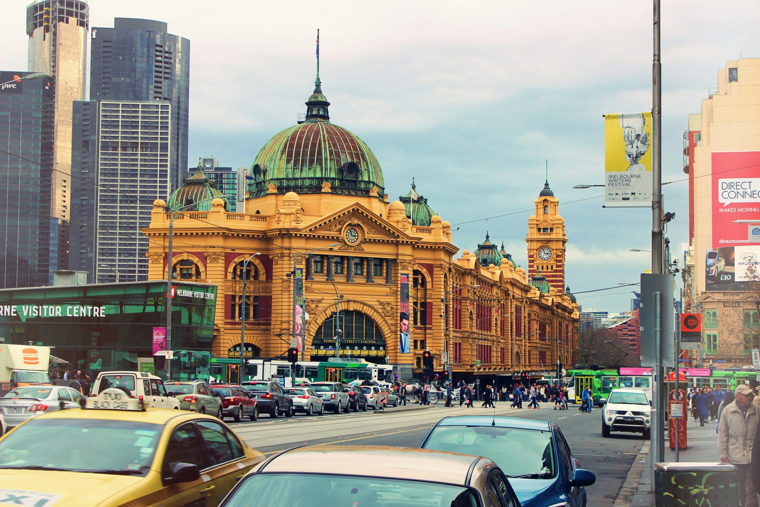 A Melbourne tram travelling along a city street with pedestrians and buildings in the background, illustrating public transport options for migrants managing the cost of living in Australia for migrants.