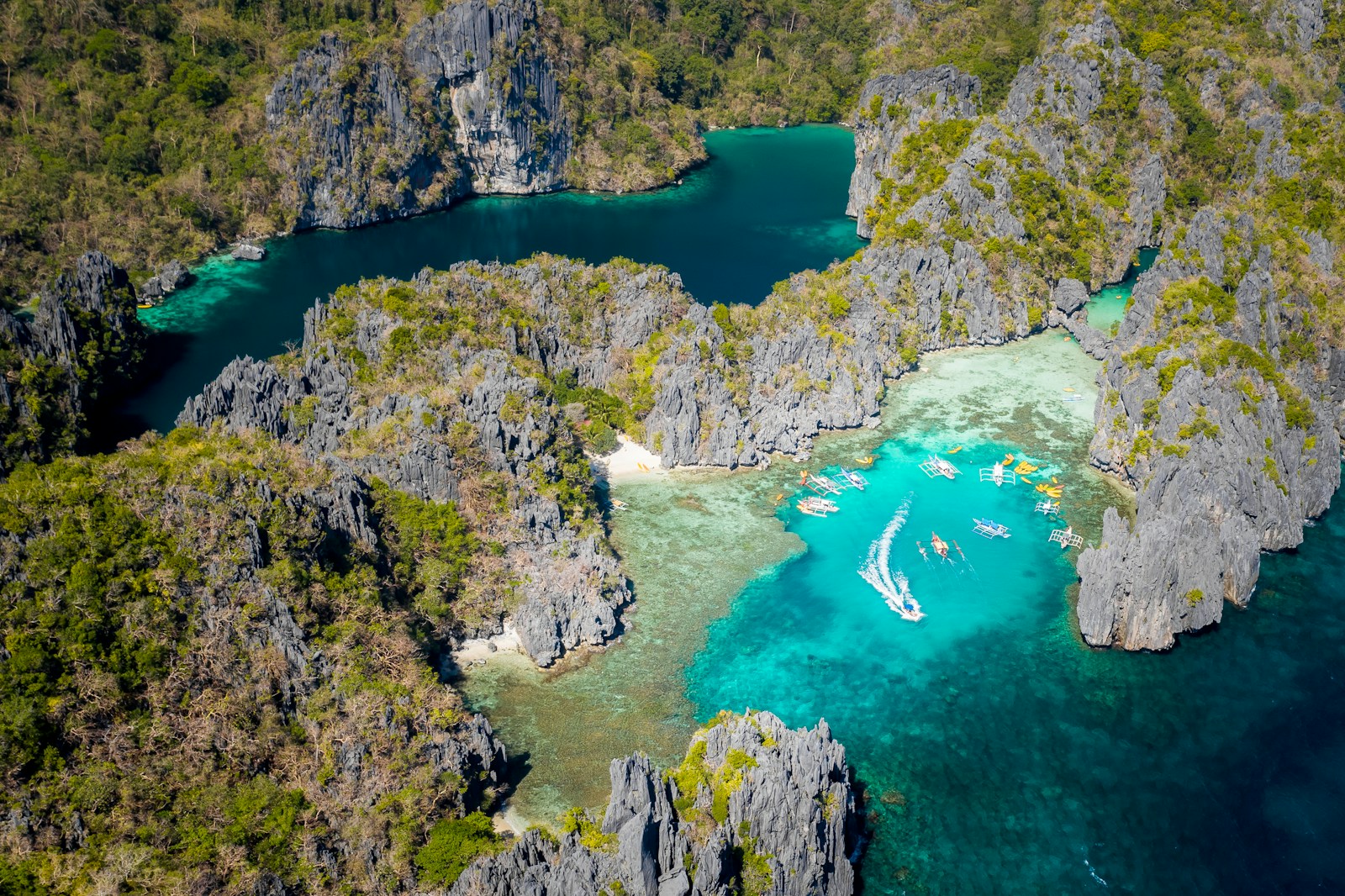 aerial view of turquoise lagoons, limestone cliffs and island-hopping boats in El Nido, Palawan