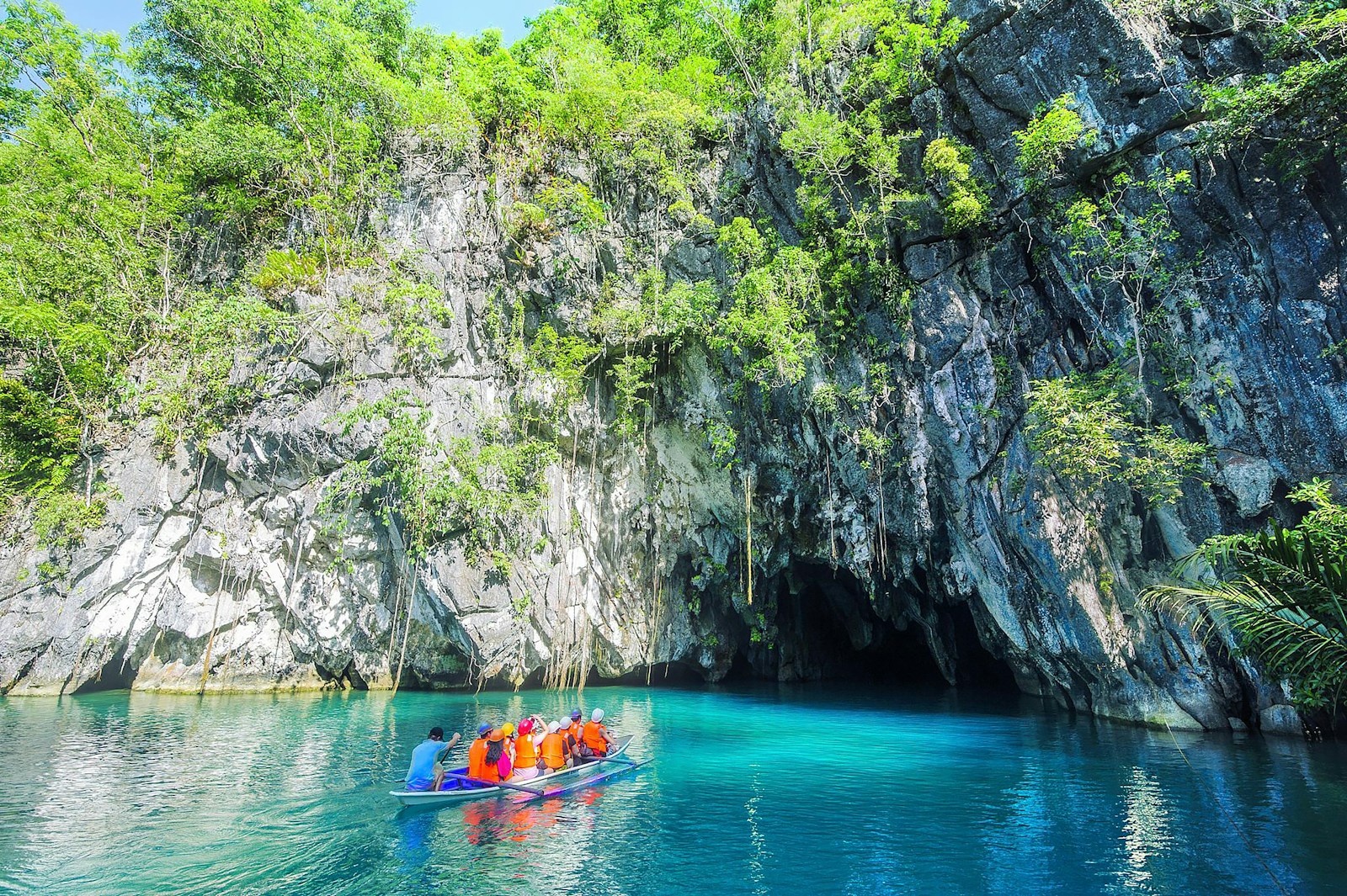 Boat entering the Puerto Princesa Underground River beneath limestone cliffs in Palawan
